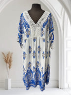 Robe bohème blanche et bleue en viscose avec un imprimé cachemire et un décolleté en V orné de dentelle. Boutique Sylbelle.