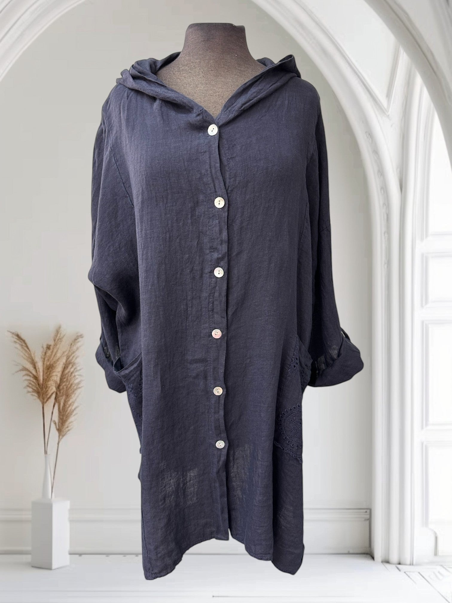 Boutique Sylbelle Veste longue en lin bleu marine à capuche, boutonnée, avec poches et détails en dentelle.